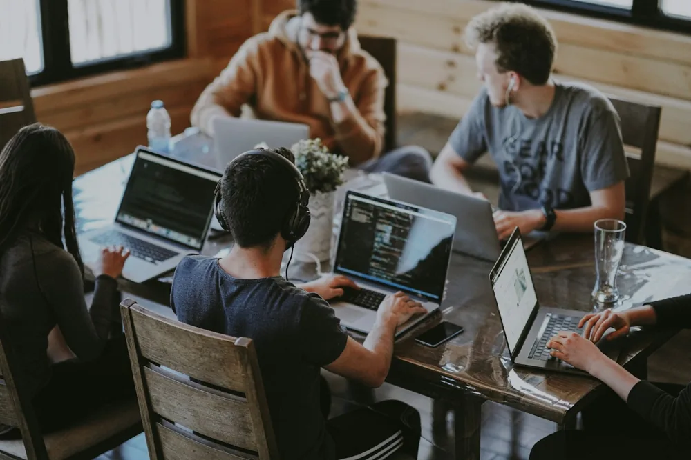 Stock photograph of adult collaborators developing a project together with laptops; not actual FAMU or 2150 participants